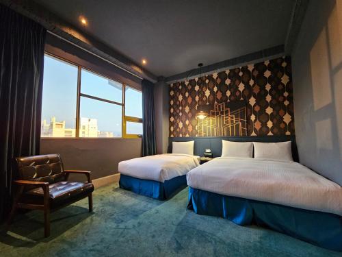 a bedroom with two beds and a chair and a window at Modern Inn in Taichung
