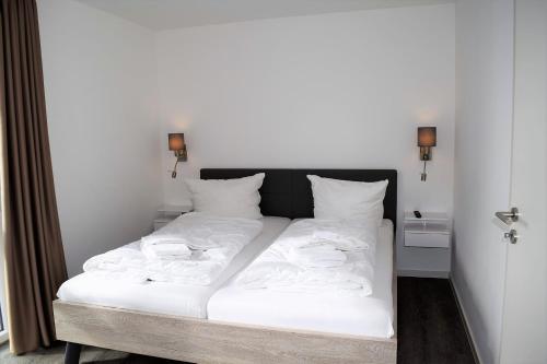 un grande letto bianco con lenzuola e cuscini bianchi di Haus Nr 23, Ferienhaus Deichgraf a Wangerland