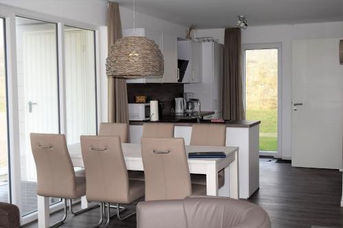 una cucina con tavolo e sedie bianchi e una sala da pranzo di Haus Nr 23, Ferienhaus Deichgraf a Wangerland