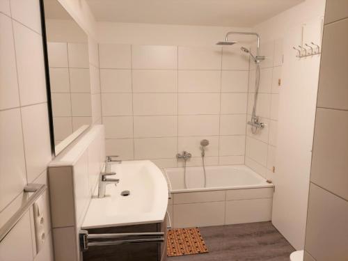 ein weißes Badezimmer mit einem Waschbecken und einer Badewanne in der Unterkunft Haus Nr 42, Ferienhaus Fischerhus in Wangerland