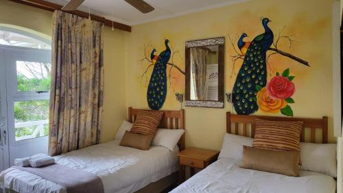 a bedroom with two beds and a window with peacocks on the wall at Caribbean Estates Montego bay 30 in Port Edward