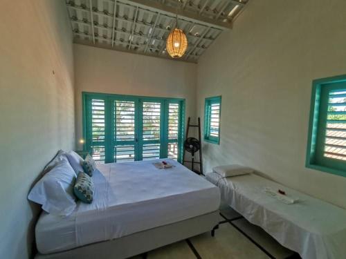 Un dormitorio con una cama y dos ventanas. en La Villa Tropicale linda casa pertinho do mar !, en Icaraí