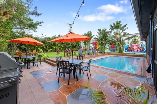 a patio with tables and umbrellas next to a pool at Unique super cozy,Bohemian Paradise with Heated Pool and positive energy in Pompano Beach