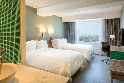 2 camas en una habitación de hotel con ventana en Fiesta Inn Ciudad de Mexico Forum Buenavista, en Ciudad de México