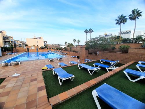 - une piscine avec des chaises longues bleues à côté d'un complexe dans l'établissement Casa El Secreto, à Playa Jandía