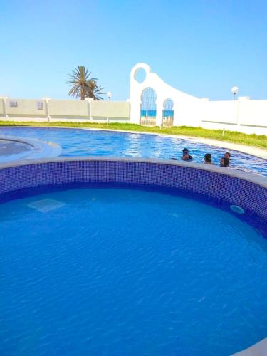 - une piscine avec des personnes à l'eau dans l'établissement One bedroom apartement with sea view shared pool and balcony at Hergla, à Harqalah