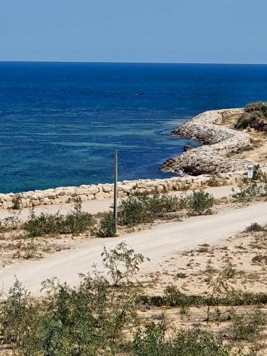 a dirt road next to the ocean on a beach at Comfortable Apartment with Sea View – Hergla – 75 m² in Harqalah