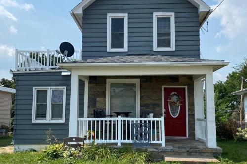 a blue house with a white porch and a red door at 3bed 2bath nestled in cozy Grandview neighborhood in Dubuque