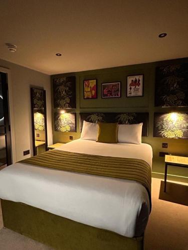 a large bed in a bedroom with two windows at The Baltic Hotel in Liverpool