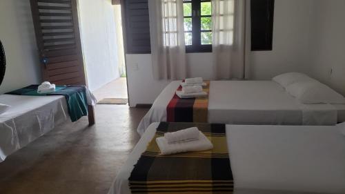 a room with two beds and a table with towels at Pousada Yemanjá Cunhaú in Barra do Cunhau
