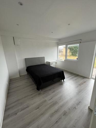 een slaapkamer met een zwart bed in een witte kamer bij Furnished 1st floor apartment with walking distance to Beach. in Abbekås