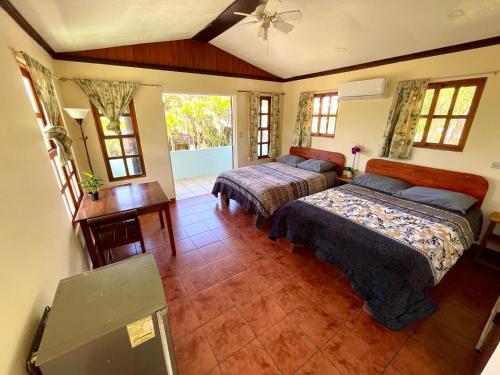 a bedroom with two beds and a table and windows at Brisa Del Mar in Playa Hermosa