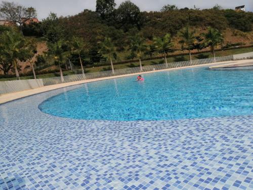 a person swimming in a large blue swimming pool at Santafé Di sole in Santa Fe de Antioquia