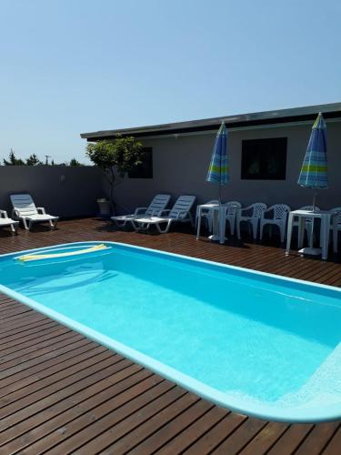 uma grande piscina num deque com cadeiras e guarda-sóis em Lindo Residencial na Praia Itapeva Torres em Torres