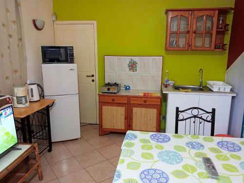 a small kitchen with a white refrigerator and a table at One bedroom appartement at Pereybere Grand Baie 350 m away from the beach with enclosed garden and wifi in Pereybere