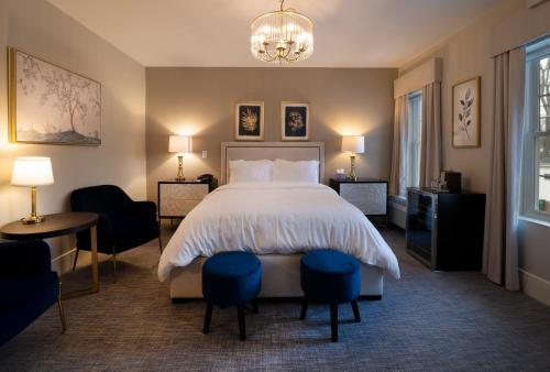 1 dormitorio con 1 cama, 2 sillas y lámpara de araña en Orange Inn Boutique Hotel, en Goshen