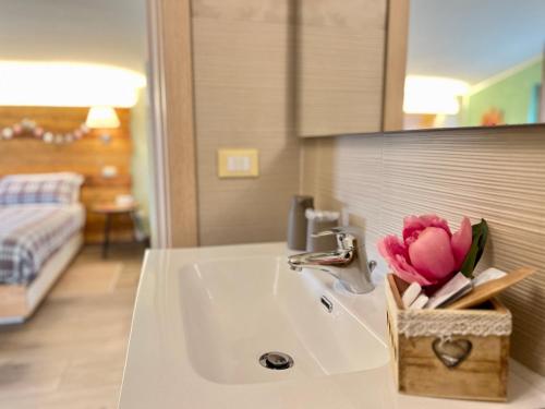 a bathroom sink with a vase of pink flowers on it at Peperosa in collina B&B in Pescara