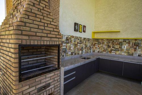 a bathroom with a brick wall with a fireplace at Muro Alto Condomínio Clube in Porto De Galinhas