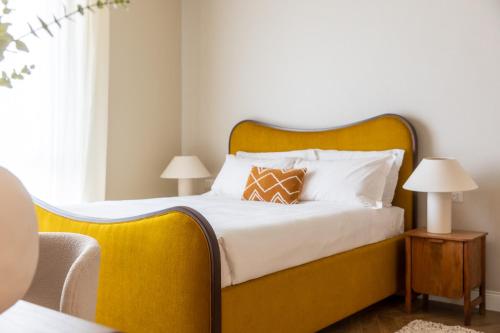 una camera con un grande letto con testiera gialla di Daplace - Corso Sempione Suites a Milano