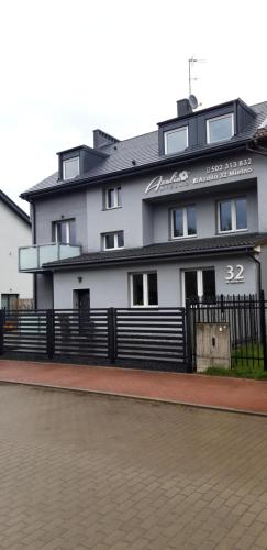 un edificio blanco con una valla negra delante en Azalia 32 Mielno l, en Mielno