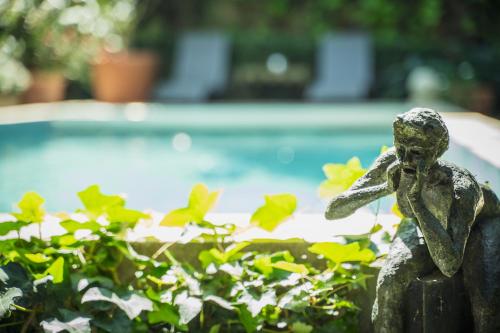 a statue of a little girl sitting next to a pool at Les Jardins de Baracane in Avignon