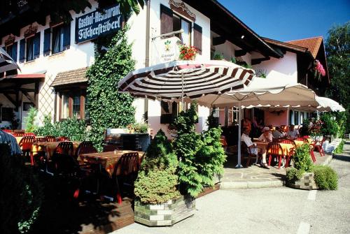 a restaurant with an umbrella in front of a building at Gasthof Fischerstüberl in Rottau