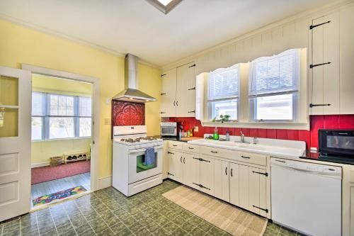 a large kitchen with white cabinets and red walls at Edenton Vacation Rental with Patio Walk Downtown in Edenton