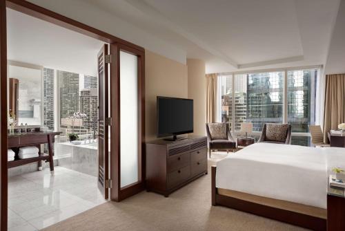 a bedroom with a bed and a television and a bathroom at Shangri-La Toronto in Toronto