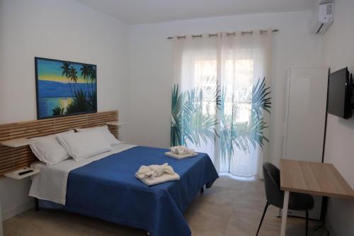 um quarto com uma cama azul, uma secretária e uma janela em B&B La Dimora di Nonno Lucio em Pozzuoli