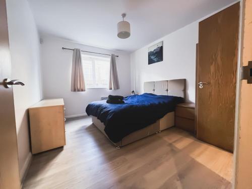 Un dormitorio con una cama azul y una ventana en Spacious 2 Bed Flat, Free Parking, Close to town, en Mánchester