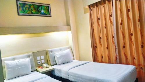 a hotel room with two beds and a window at Permata Inn Slawi in Procot