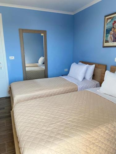 two beds in a room with a blue wall at Persephone in Himare