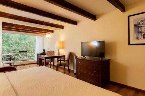 a bedroom with a television and a table with chairs at Hotel Villa Mercedes San Cristobal in San Cristóbal de Las Casas