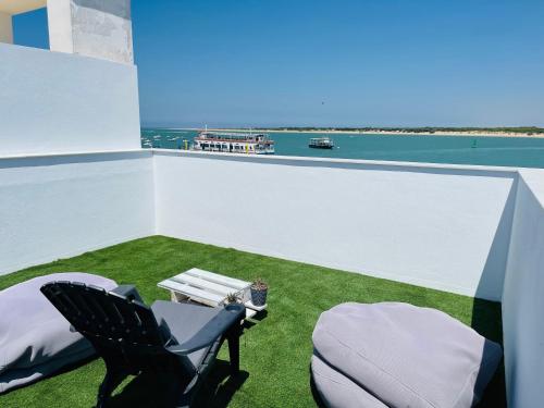 a balcony with two chairs and a table and the ocean at Duplex ático Bajo de Guía in Sanlúcar de Barrameda