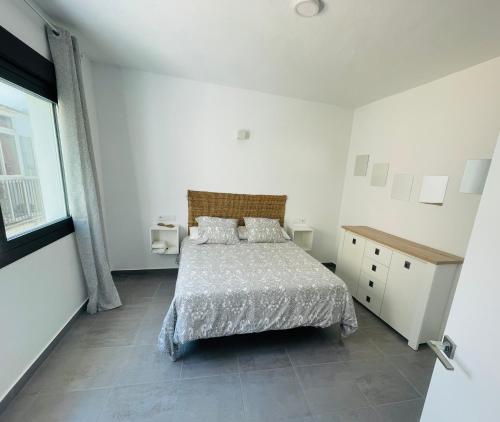 a white bedroom with a bed and a window at Duplex ático Bajo de Guía in Sanlúcar de Barrameda
