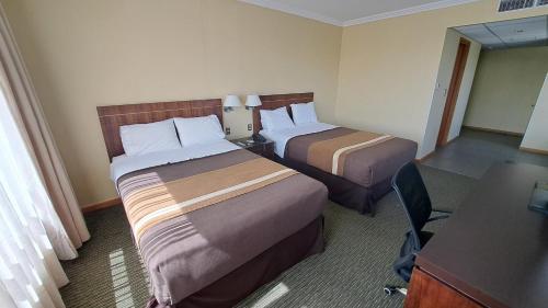a hotel room with two beds and a desk at Hotel Diego de Almagro Temuco in Temuco