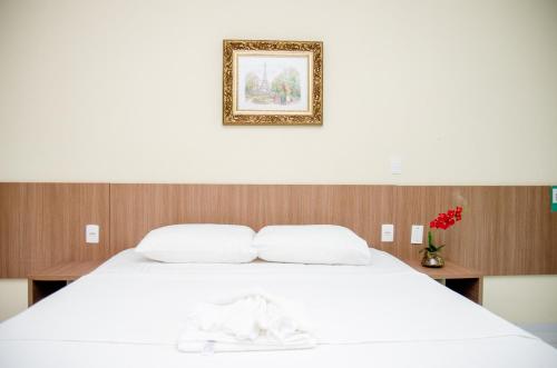 a bedroom with a white bed with a picture above it at Hotel Acarau Riviera in Acaraú