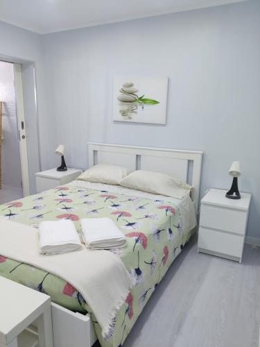 a white bedroom with a bed with towels on it at Riviera Beach B in Praia da Vitória