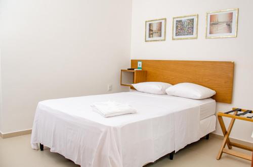 a bedroom with a white bed with a wooden headboard at Hotel Acarau Riviera in Acaraú