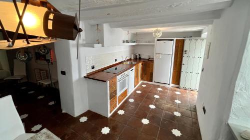 a kitchen with white appliances and a brown tile floor at Casa Casco Historico in Frigiliana