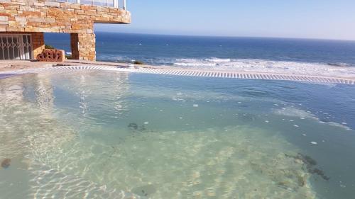 ein Schwimmbad mit dem Ozean im Hintergrund in der Unterkunft Seaside Tresure. in Mossel Bay