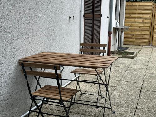 une table et une chaise en bois installées à côté d'un bâtiment dans l'établissement Maison de Longde-Appartement avec 2 chambres, à Villejuif