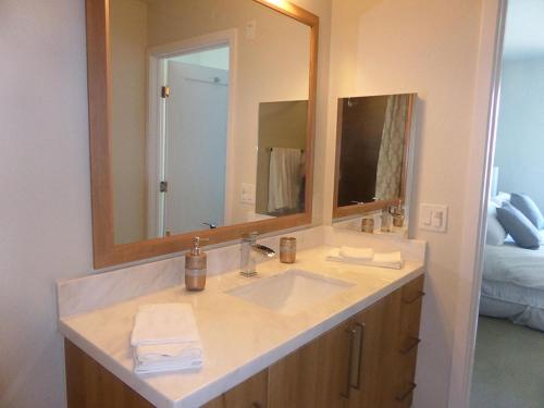 a bathroom with a sink and a large mirror at Masterpiece 2-Bedroom with Balcony, Pool, and Spa in Los Angeles
