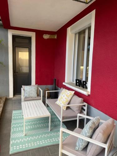 a porch with two chairs and a window and red wall at Maison rouge in Millau