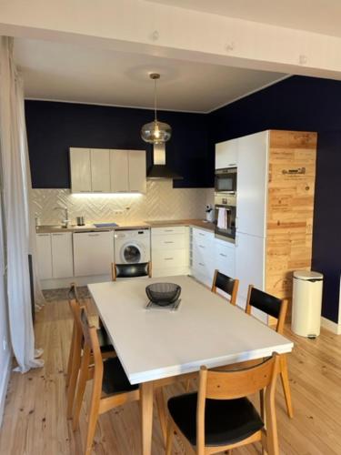 a kitchen with a white table and chairs and a kitchen with blue walls at Maison rouge in Millau