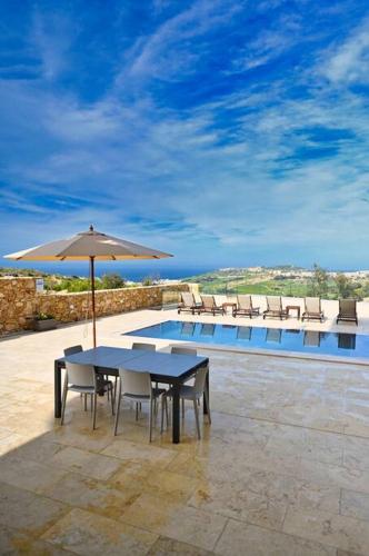 a table and chairs with an umbrella next to a pool at Luxurious Maisonette with Pool & Hot tub in Xaghra in Tal-Barmil