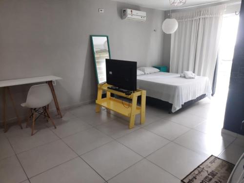 een slaapkamer met een bed, een spiegel en een televisie bij Hotel Oiticica in Fortaleza
