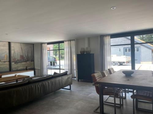 a living room with a couch and a table with chairs at Landelijk gelegen vakantiehuis met hottub! in Tollebeek