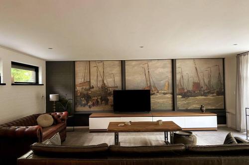 a living room with a large painting of ships on the wall at Landelijke gelegen woning voor 6 personen met hottub! in Tollebeek