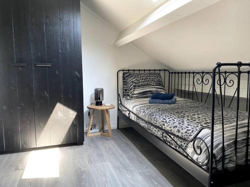 Schlafzimmer mit einem schwarzen Bett und Holzboden in der Unterkunft Landelijk gelegen vakantiehuis met hottub! 